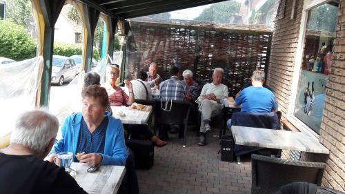 Enkele deelnemers zitten voor de lunch op het overdekte terras aan de zijkand van het cafe