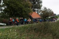 Een groot peloton rijdt tegen de wind in tijdens de laatste tandemtocht van Piet Brocatus